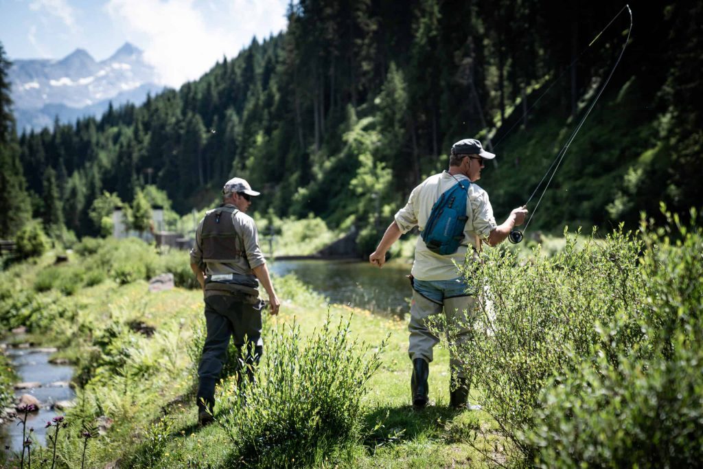 Angler am Ufer eines Flusses im Nationalpark Hohe Tauern, umgeben von Naturkulissen.