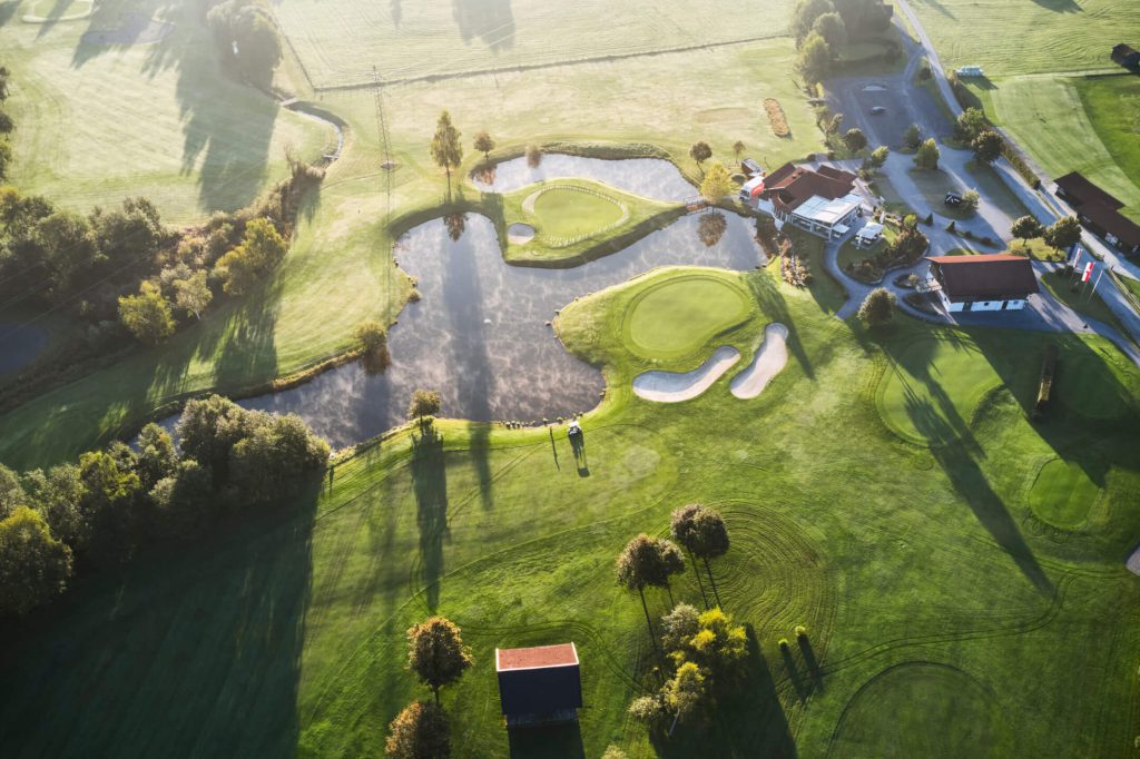 Luftaufnahme des Golfplatzes Mittersill mit Teich und gepflegten Greens in Naturkulisse.