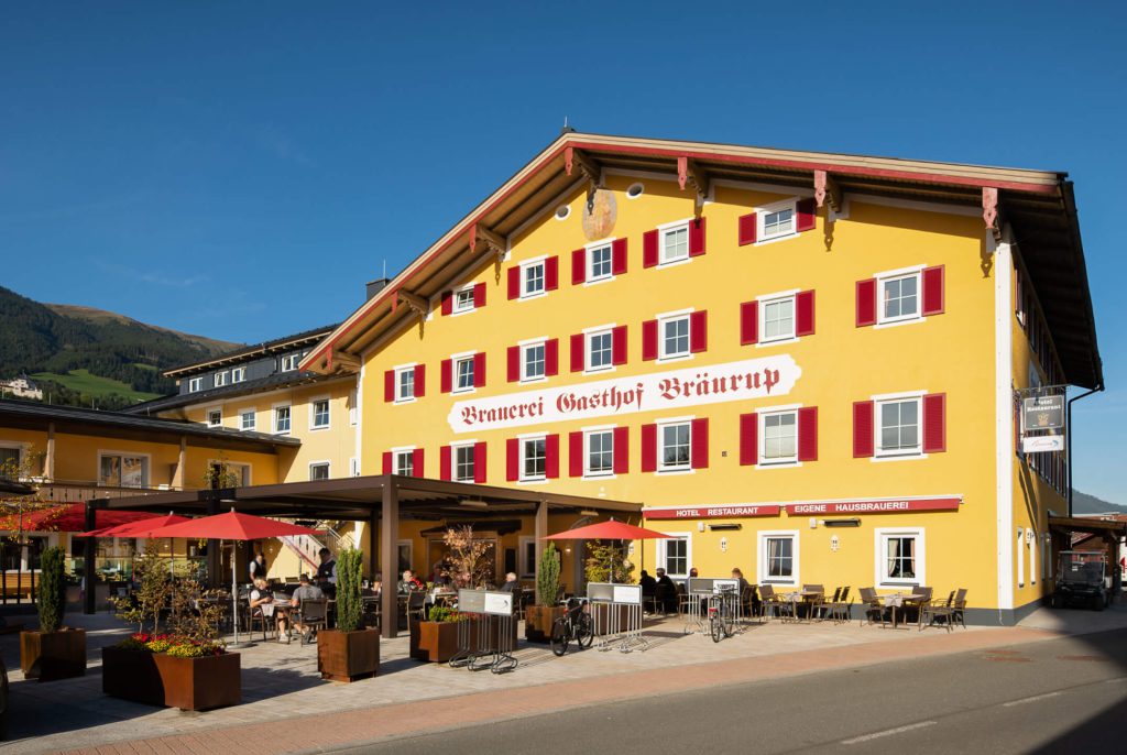 Hotel Bräurup in gelber Fassade mit Terrassenbereich in den Bergen des Nationalparks Hohe Tauern.